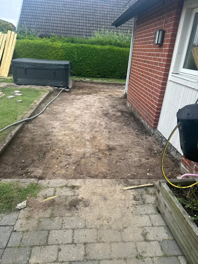 Före: marken uppgrävd och avjämnad längs fasaden, redo för regelverket.