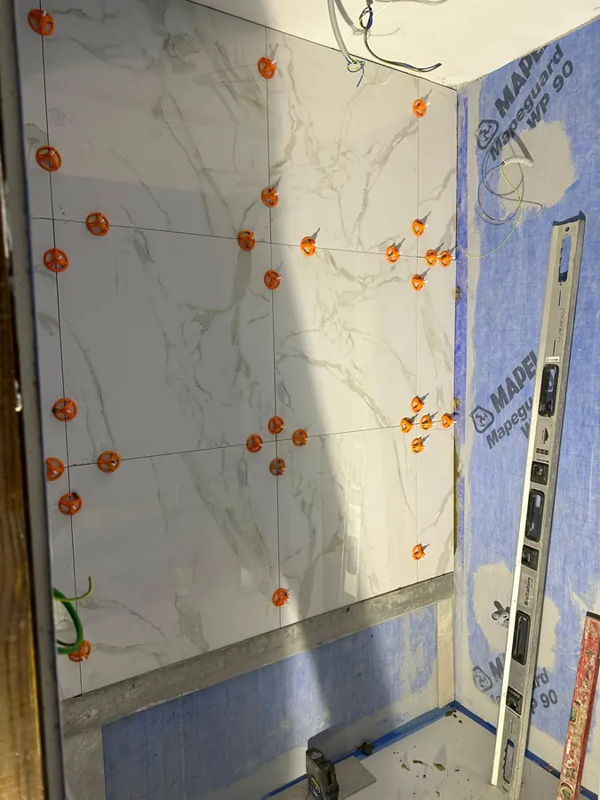 Storformatsplattorna sätts med nivåclips, vattenpasset kontrollerar varje rad.