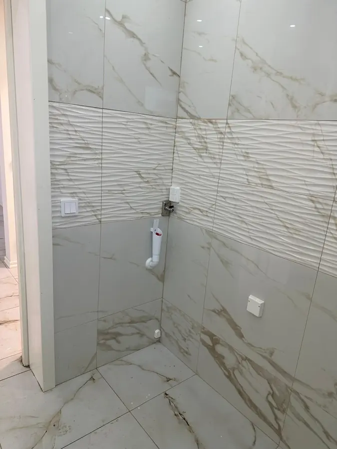 Färdigkaklat hörn med anslutning för tvättmaskin, uttag och strömbrytare.